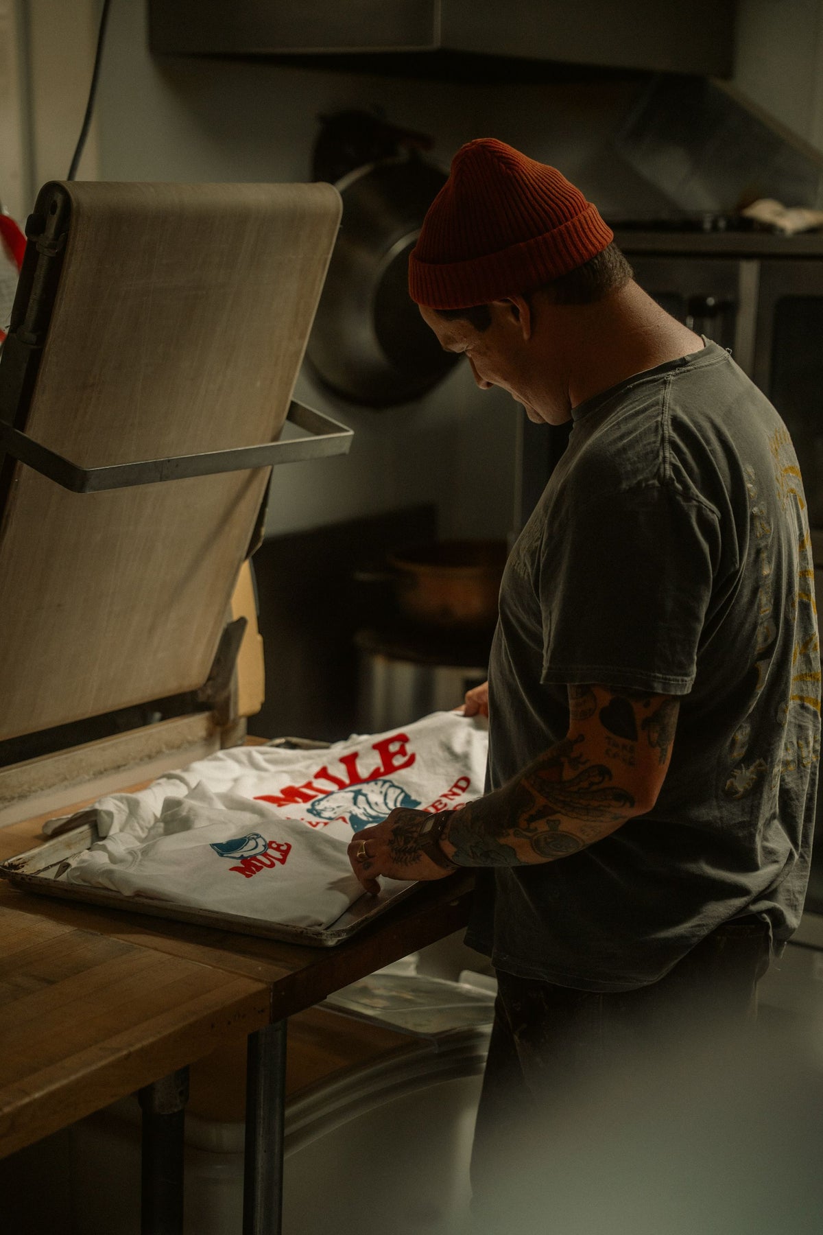 Artisan positionnant un t-shirt blanc imprimé d'un logo sur le plateau d'une presse à chaud ouverte