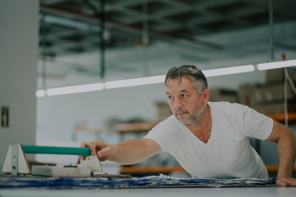 Opérateur d'atelier textile passant une raclette sur un tissu imprimé, étape de production du marquage