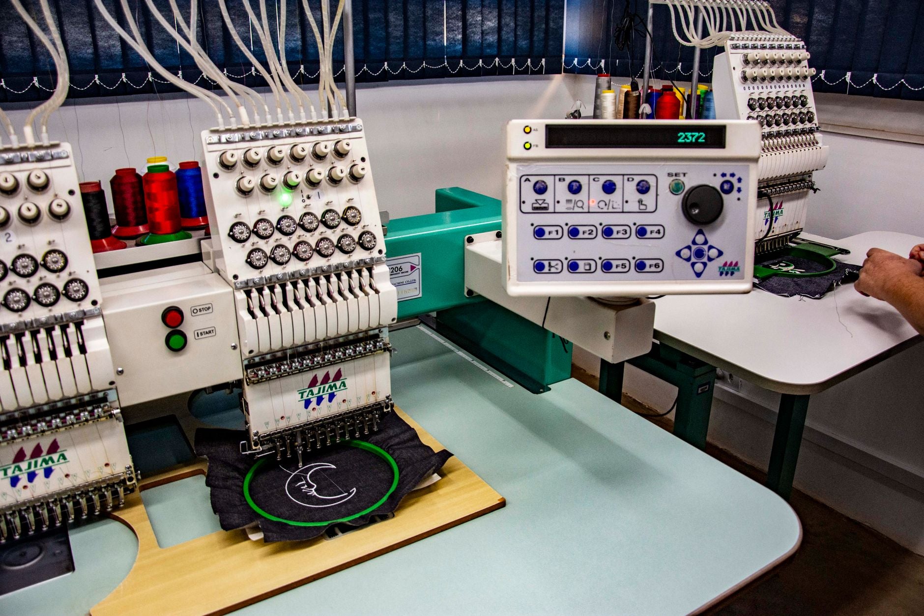 Machine à broder industrielle brodant un logo sur un vêtement en atelier