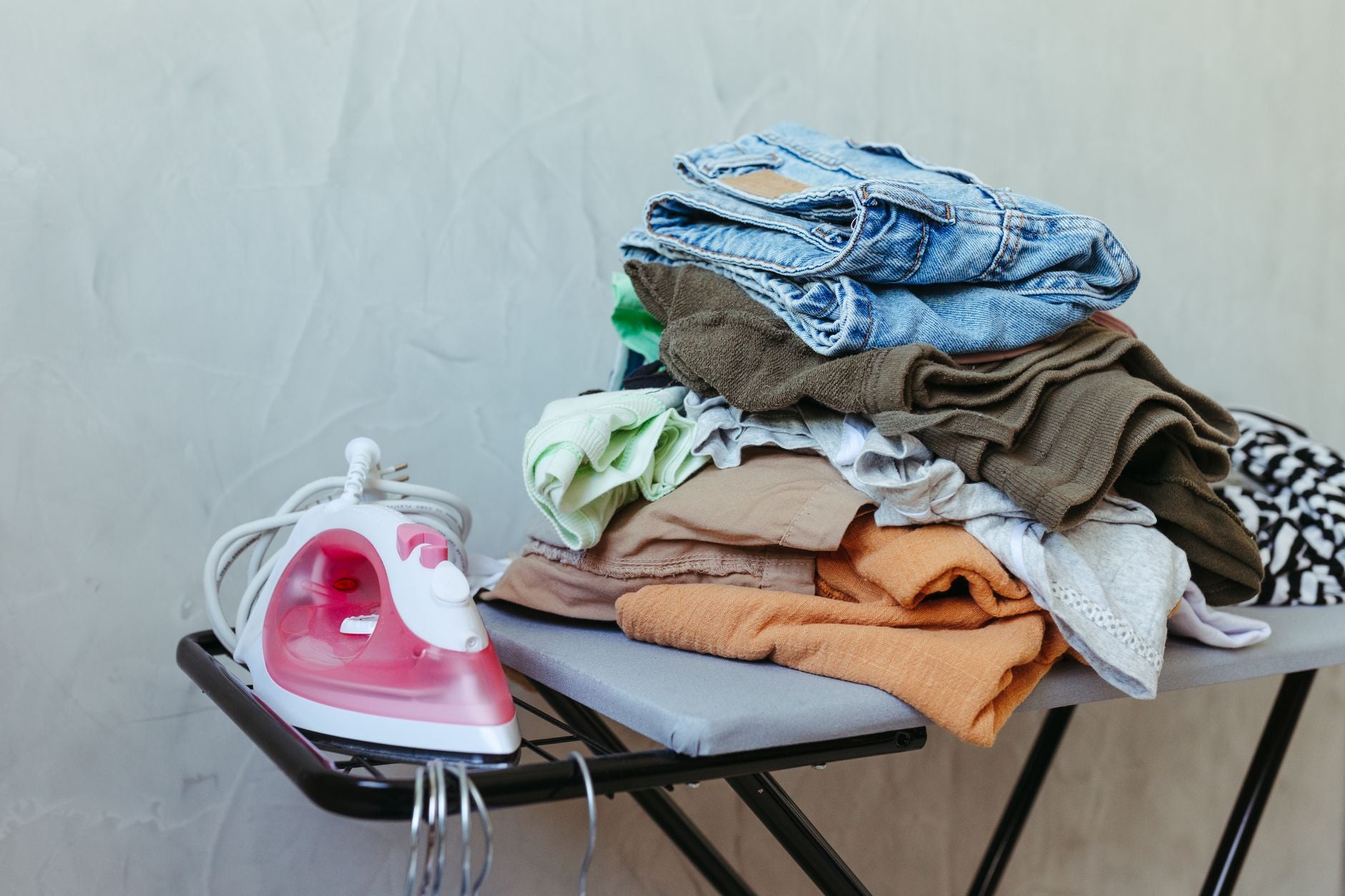 Pile de vêtements textiles à côté d'un fer, avant application d'un transfert DTF à la presse à chaleur