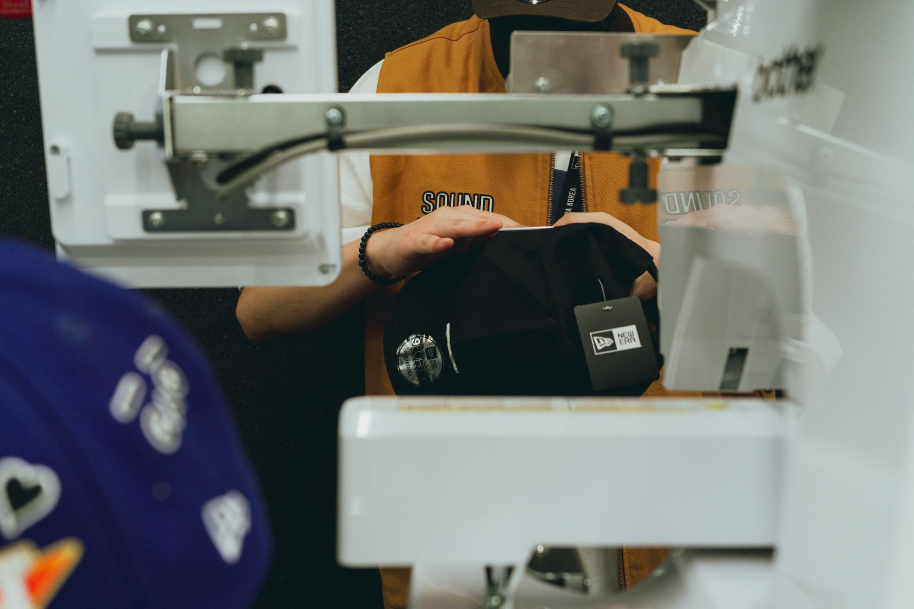 Casquette manipulée près d'une presse en atelier de personnalisation