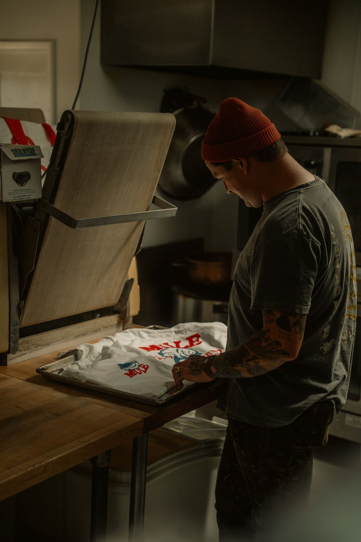 Presse à chaud ouverte dans un atelier, t-shirts blancs imprimés posés sur la platine