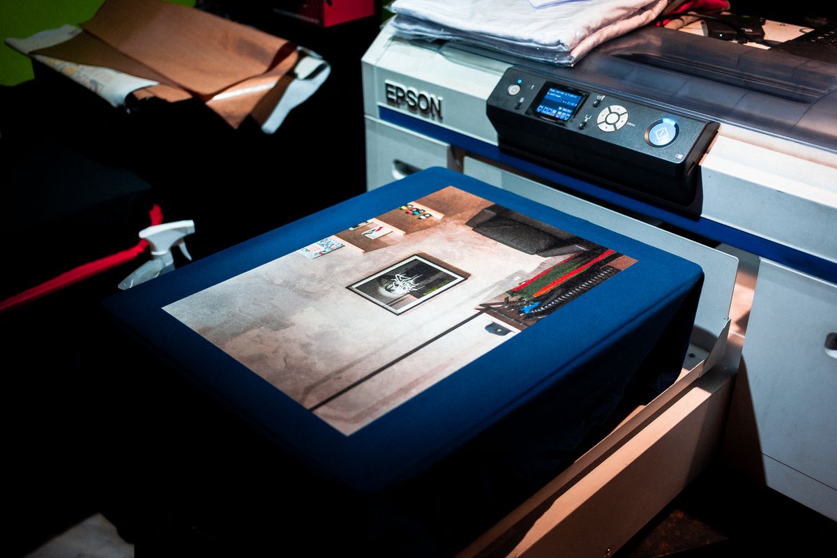 Imprimante DTF à plat imprimant un motif sur un vêtement avant transfert par pressage