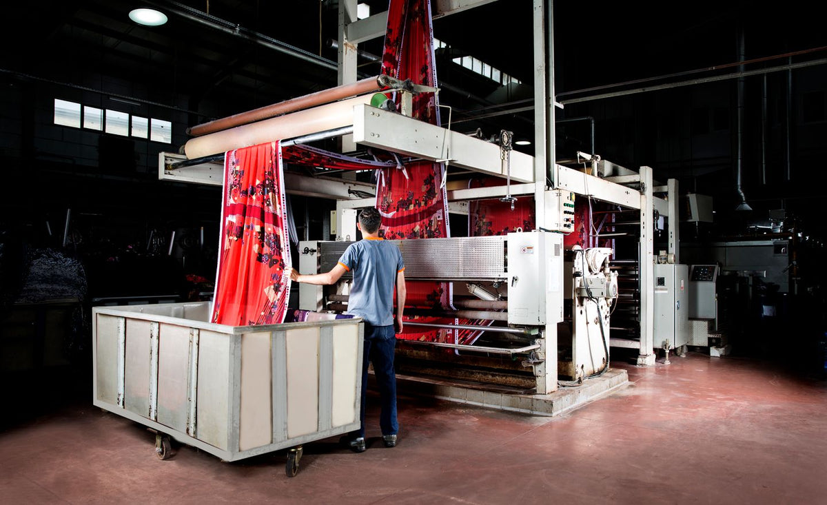 Machine industrielle de production textile en continu dans un atelier, tissu imprimé en sortie